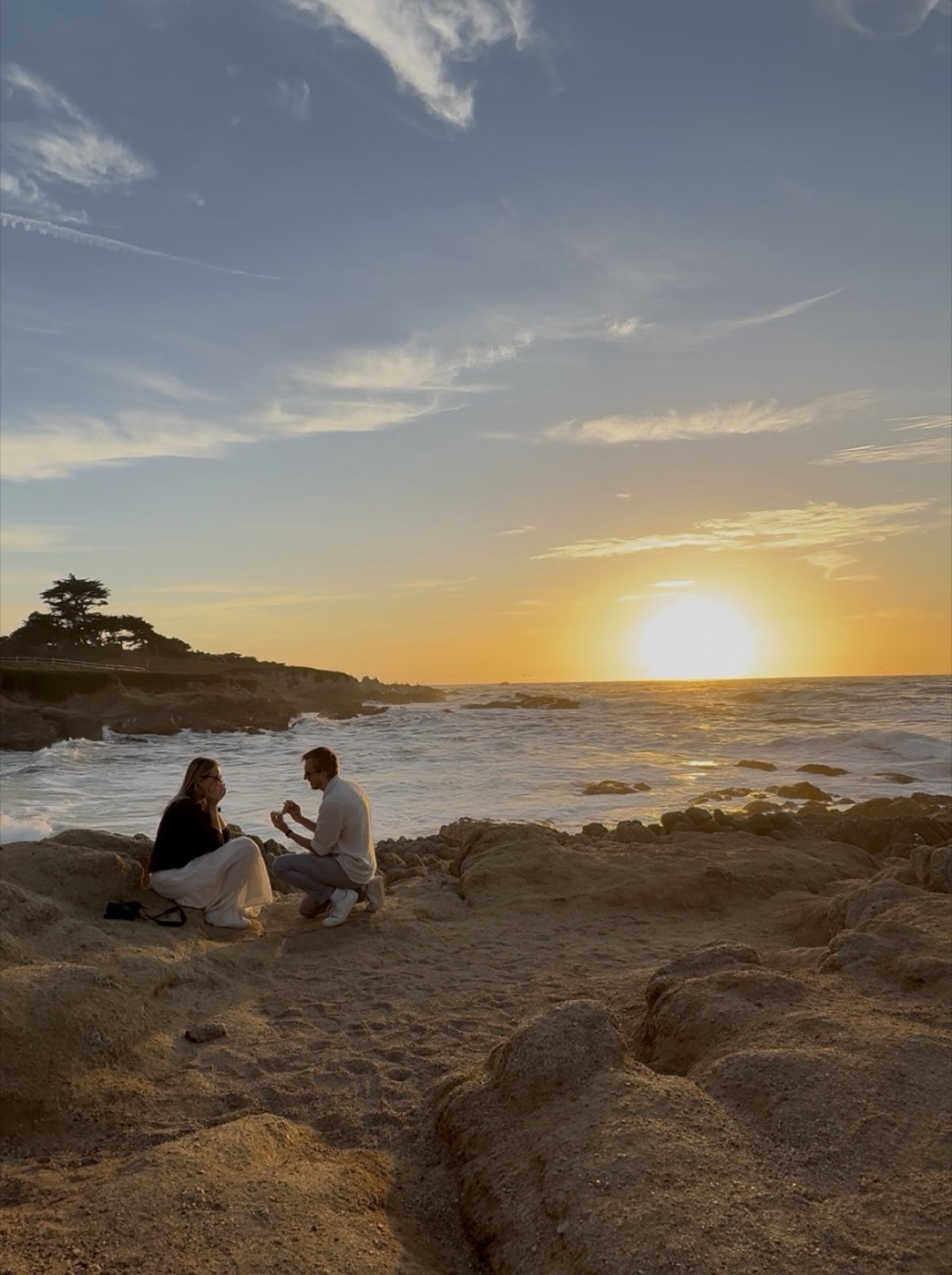 Nikolas proposing to Patricia on a rocky beach at sunset