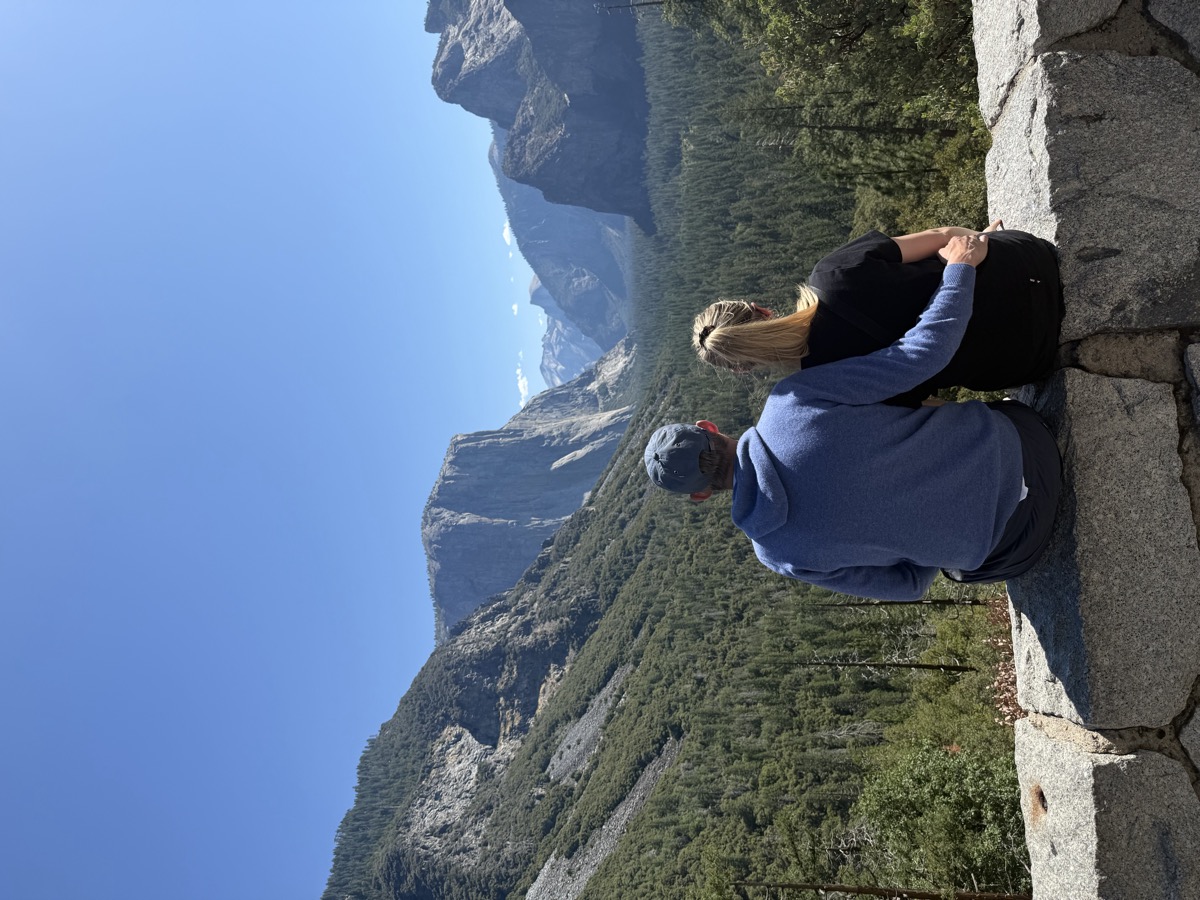 Patricia and Nikolas sitting on a stone wall looking out over Yosemite Valley